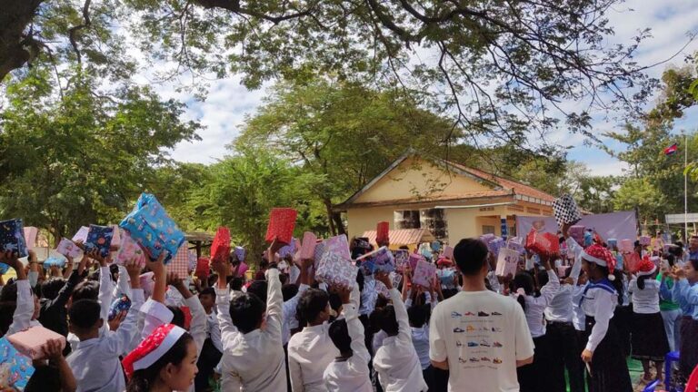 Photo of Cambodia school kids holding up their gifts